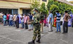 People stand in a queue to cast their votes at a polling