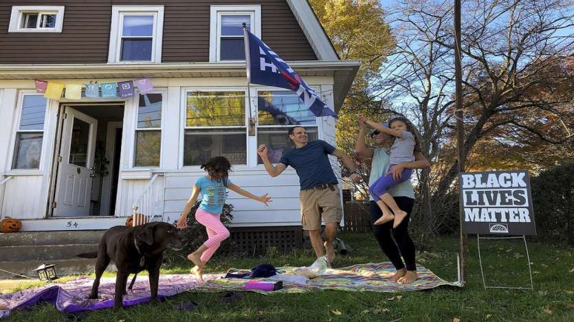 From left, 7-year-old Nina, her father Greg Healey and Julia Healy dance with 5-year-old Liza Healy, and dog is Stella as cars pass by honking horns in celebration after former vice president and Democratic presidential candidate Joe Biden was announced as the winner over Pres. Donald Trump to become the 46th president of the United States, in Nyack, N.Y.