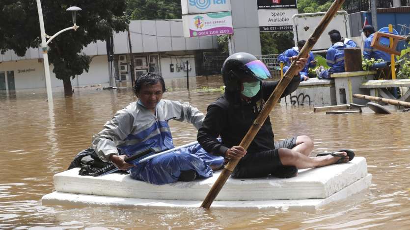 Residents use a cork material as a raft to make their way through a flooded street following heavy rains in Jakarta, Indonesia. 