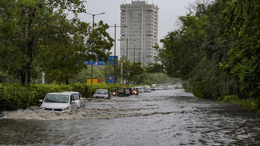 Commuters wade through waterlogged street due to heavy rains in New Delhi.